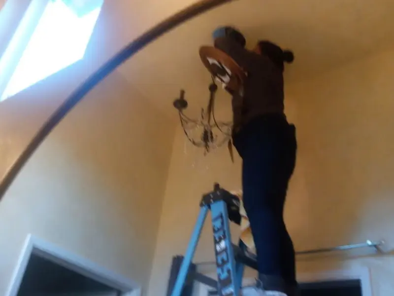 Electrician installing a chandelier in a Barnegat residence